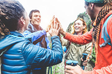 Group of happy trekkers stacking hands outdoor - Young hiker friends supporting each others - Survival, team, travel, success and adventure concept - Focus on hand