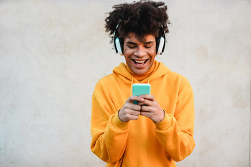 Happy african millennial guy listening music playlist with smartphone app outdoor - Young man having fun with technology trends - Tech, generation z and stylish concept - Focus on face