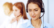 © rogerphoto - Call center operators. Focus on beautiful business woman using headset in sunny office
