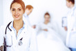 © rogerphoto - Female doctor smiling on the background with patient in the bed and two doctors