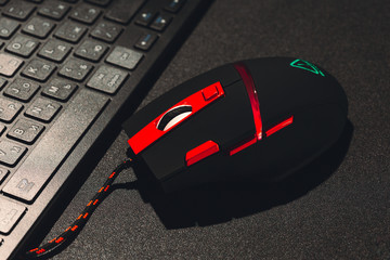 PC mouse with red buttons and keyboard on black background