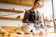 © LIGHTFIELD STUDIOS - selective focus of happy woman sieving flour in glass bowl near raw eggs on table