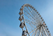 Modern Ferris Wheel On A Blue Sky Background. Huge Ferris Wheel With Cabins.
