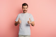 © LIGHTFIELD STUDIOS - smiling handsome man showing thumbs up while looking at camera on pink background