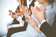 © rogerphoto - Business people clapping and applause at meeting or conference, close-up of hands. Group of unknown businessmen and women in modern white office. Success teamwork or corporate coaching concept