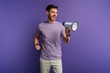 © LIGHTFIELD STUDIOS - irritated young man screaming in megaphone while looking away on purple background