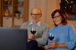 © Syda Productions - holidays, drinks and people concept - happy smiling senior couple with glasses of red wine watching tv at home in evening
