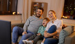 © Syda Productions - family, leisure and people concept - happy smiling father, mother and little son with remote control watching something funny on tv at home at night