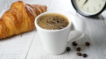 Wall Mural - dark coffee pouring in cup with croissant and alarm clock concept