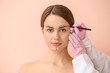 © Pixel-Shot - Plastic surgeon applying marking on female face against color background