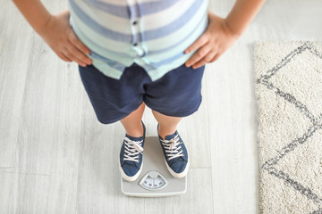Overweight boy standing on scales at home
