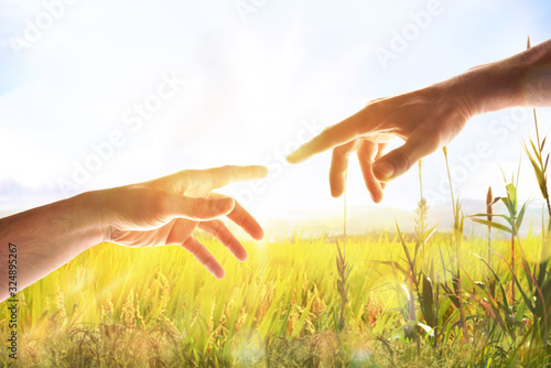 Photographie Two hands with fingers that almost touch in field