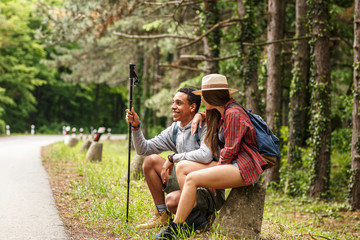 Wall Mural - two friends hiking in nature.they sitting and resting by the old country road.
