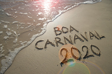 Wall Mural - Boa Carnaval 2020 message, Portuguese for Happy Carnival, handwritten on smooth sand beach with incoming wave  in Rio de Janeiro, Brazil. Translation: Happy Carnival