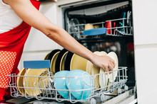 Woman Taking Out Clean Dishes From Dishwasher Machine..