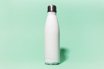 Close-up of white reusable steel stainless thermo water bottle isolated on background of aqua menthe color. Plastic free.