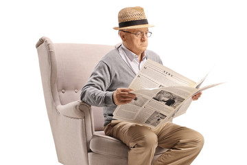 Sticker - Senior man sitting in an armchair and reading a newspaper