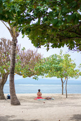 sitting on sandy white beach under the tree in sanur bali, indonesia