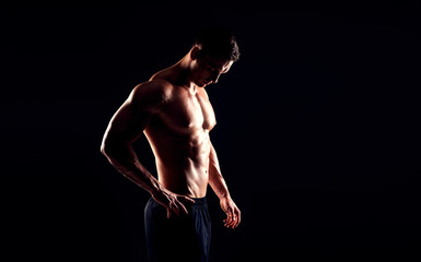 Wall Mural - Strong, fit and sporty bodybuilder man over black background.