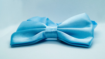 Blue satin bow tie on a white background. Stylish holiday accessory. The concept of fashion and holidays.