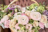 Fototapeta Storczyk - Flowers delivery. Flower arrangement in large Wicker basket. Beautiful bouquet of mixed flowers in woman hand. Floral shop concept . Handsome fresh bouquet.