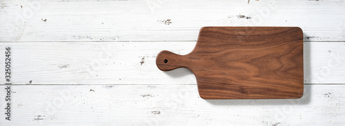 Fotografía Handmade walnut wood cutting board on white wooden board desktop.