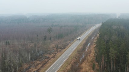 Wall Mural - Aerial view over the highway with traffic in the fog, forest landscape.
