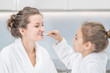 © Ermolaev Alexandr - Young girl brushes mom`s teeth with toothbrush at home
