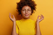 © wayhome.studio  - Headshot of calm healthy young woman closes eyes and does meditation gesture with fingers, wears spectacles and yellow shirt, tries to find peace inside of body, practices yoga, poses indoor