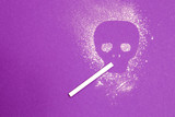 Fototapeta  - skulls made of white starch, cigarette in the teeth of the skull, purple background, copy space, harm to smoking concept, deadly habit