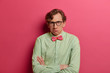 © WHstudio Leushin N - Embarrassed hesitant man looks confusingly at camera, crosses hands, has unaware face expression, thinks about changing job position, dressed formally, has serious look, isolated on pink background