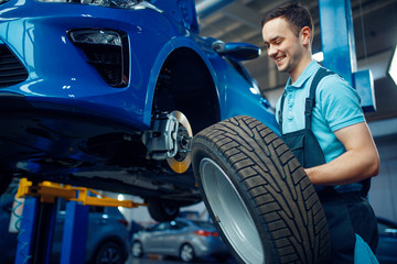 Wall Mural - Worker removes wheel from vehicle, car service