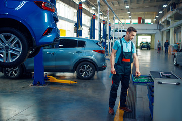 Wall Mural - Repairman stands at vehicles on lifts, car service