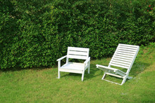 Two Empty White Colored Wooden Chairs In The Sunshine Garden
