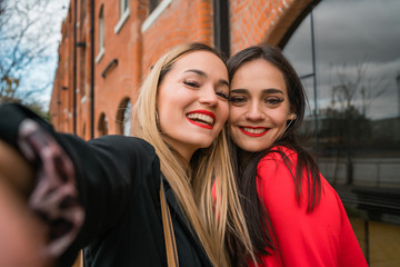 Wall Mural - Two young friends taking a selfie outdoors.