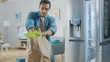 © Gorodenkoff - Handsome Attractive Young Man Brings Groceries to the Kitchen. He Bought Fresh Salad Greens. Modern Fridge is on the Background. Room Has Bright Modern Interior.