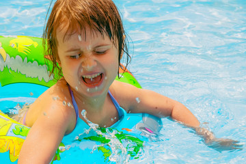 Funny portrait of happy cute little child girl playing in swimming pool.