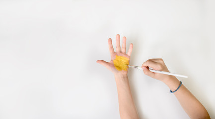 Close up photo of child who paint his hand with yellow paint