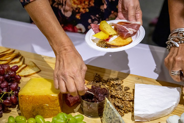 people cutting meat and cheese on wooden board