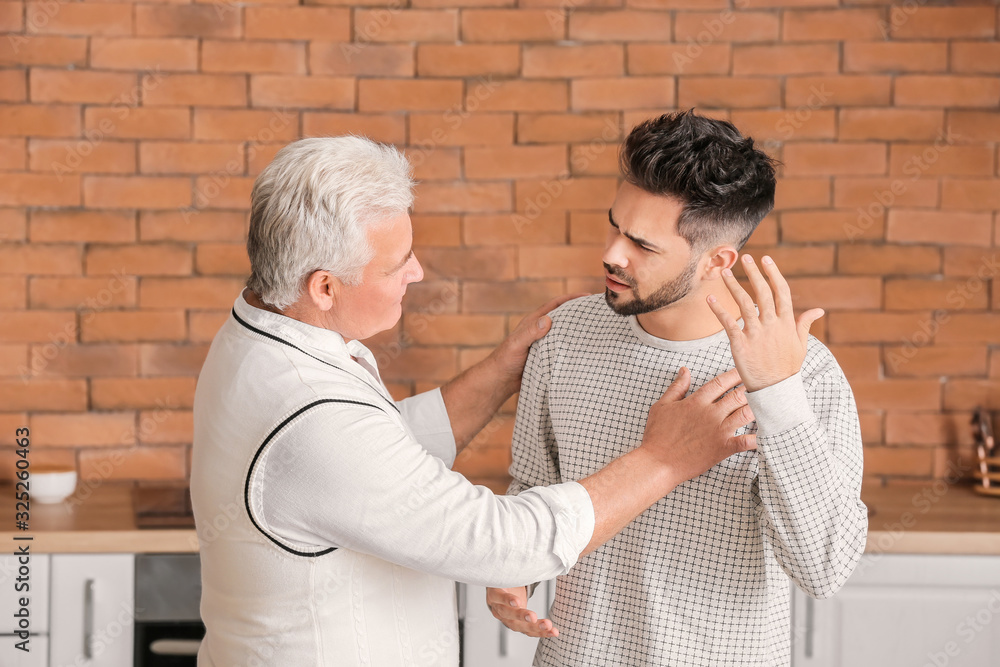 Young man and his father arguing in kitchen