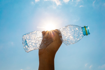  Hand squeeze plastic bottle and sun shining in the blue sky background