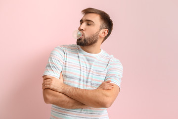 Funny man with chewing gum on color background