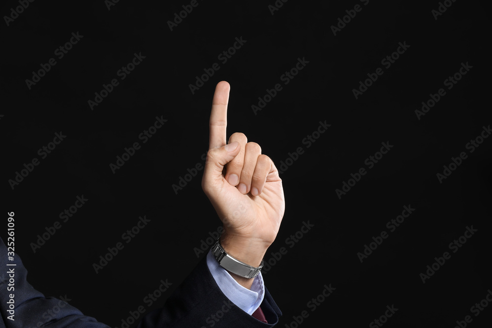 Young businessman using virtual screen on dark background