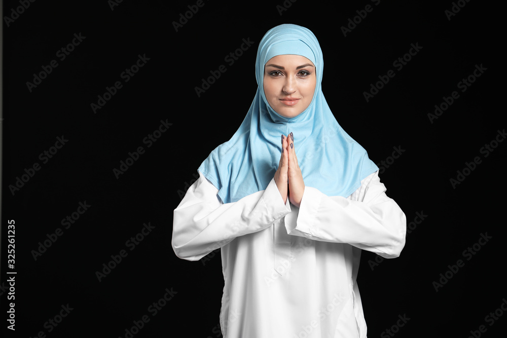 Beautiful praying Arab woman on dark background