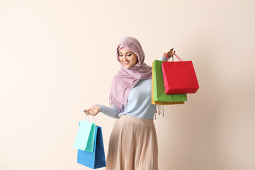 Poster - Young Arab woman with shopping bags on color background