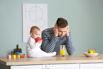 Poster - Young man suffering from postnatal depression in kitchen