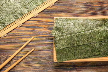 Tasty seaweed sheets and chopsticks on table