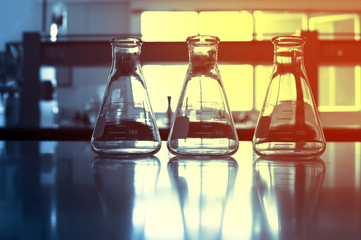 Wall Mural - three glasses flask on chemistry science laboratory blue background