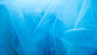 A blue tulle fabric is used as a background with copy space. Sewing concept.