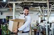© Dusan Petkovic - Smiling caucasian bearded graphic engineer in shirt and tie walking in printing shop and relocating box. In background are printing machines.